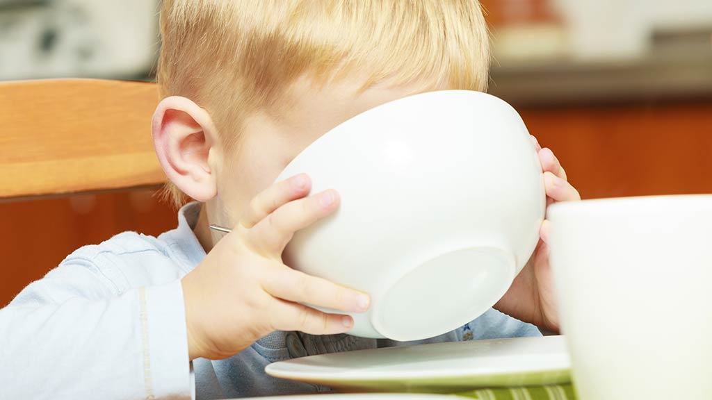 little boy drinking with cereal bowl